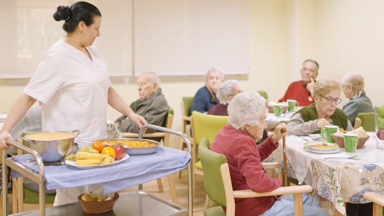 Cocinero sirviendo la comida en el comedor de una residencia de mayores